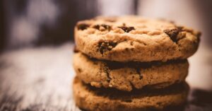 A macro shot of freshly baked stacked chocolate chip cookies creates a cozy dessert vibe.
