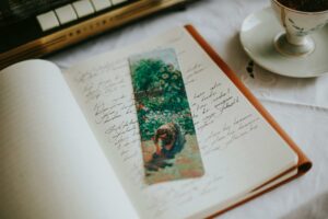 A cozy scene featuring a notebook with handwritten notes, an art bookmark, and a cup of tea, perfect for creatives.